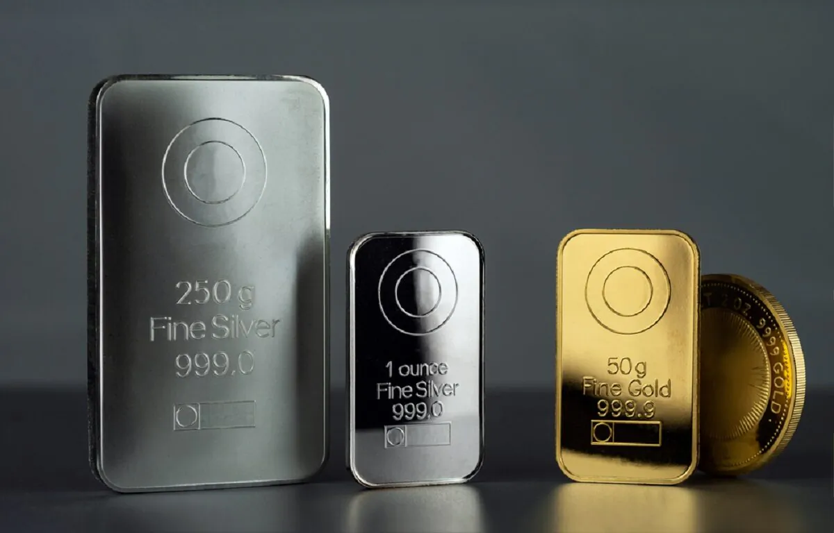 Silver and gold bars and coin on a dark background. (VladKK/Shutterstock)
