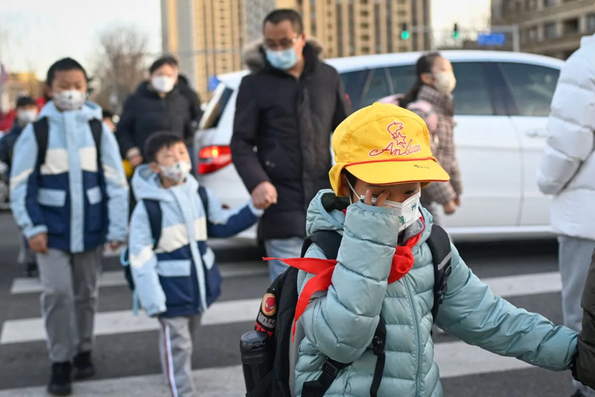 Elementary school students are accompanied by their parents as they walk to school on the first day of the new semester in Beijing on February 13, 2023. (WANG ZHAO/AFP via Getty Images)