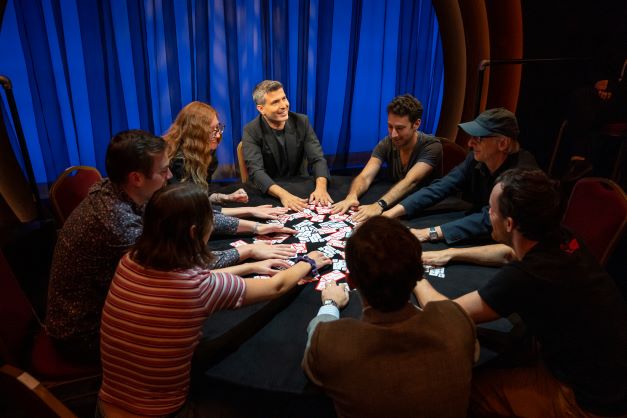 Magician Asi Wind at the card table with audience members. (Joan Marcus)