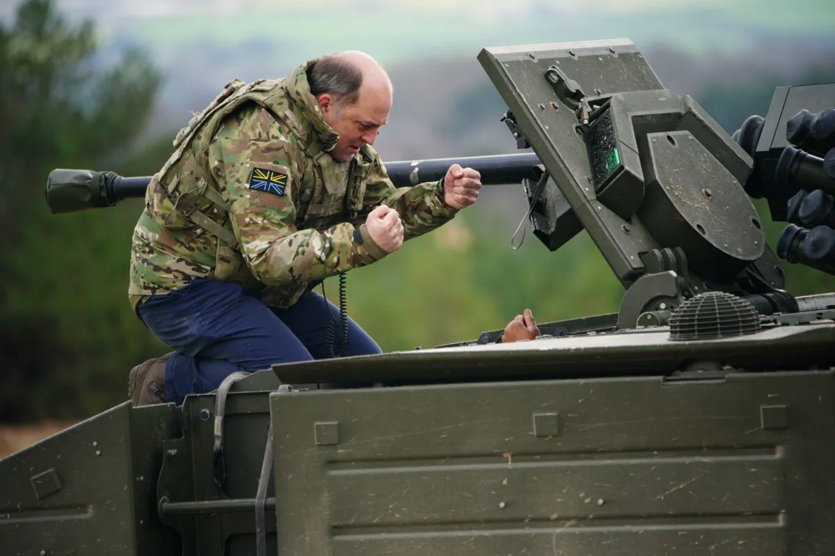 Defence Secretary Ben Wallace speaks to the crew inside an Ajax armoured personnel at Bovington Camp, England, on Feb. 22, 2023. (Ben Birchall/PA Media)