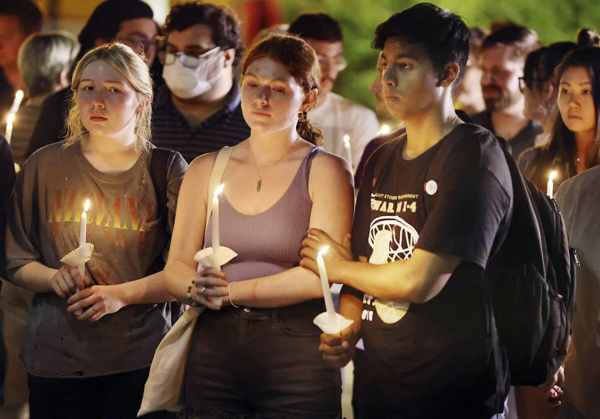 UCF students grieve during a candlelight vigil for slain News 13 journalist Dylan Lyons outside the Nicholson School of Communication and Media on the campus of Central Florida University, in Orlando, Fla., on Feb. 24, 2023. (Stephen M. Dowell/Orlando Sentinel via AP)
