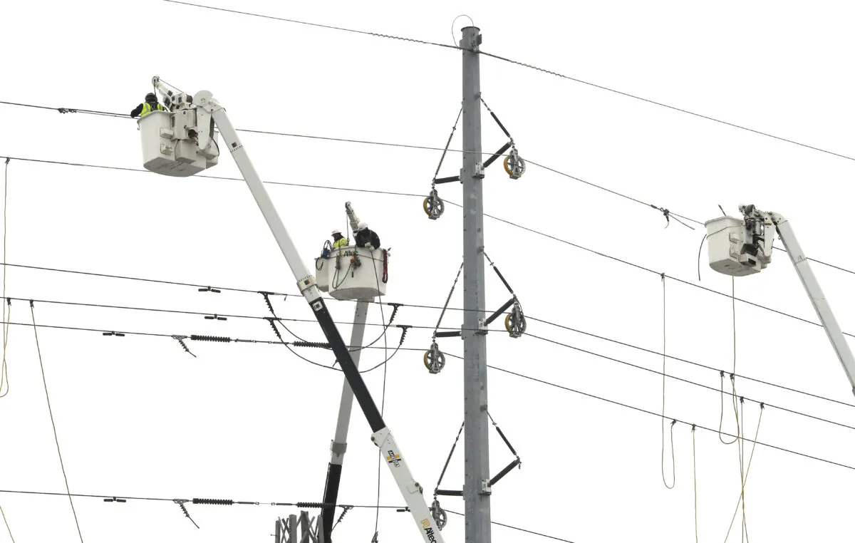 ITC Transmission, a subsidiary of DTE Energy, basket trucks work on power lines along 8 Mile, near Wanda in Ferndale, Mich., on Feb. 25, 2023. (Daniel Mears/Detroit News via AP)