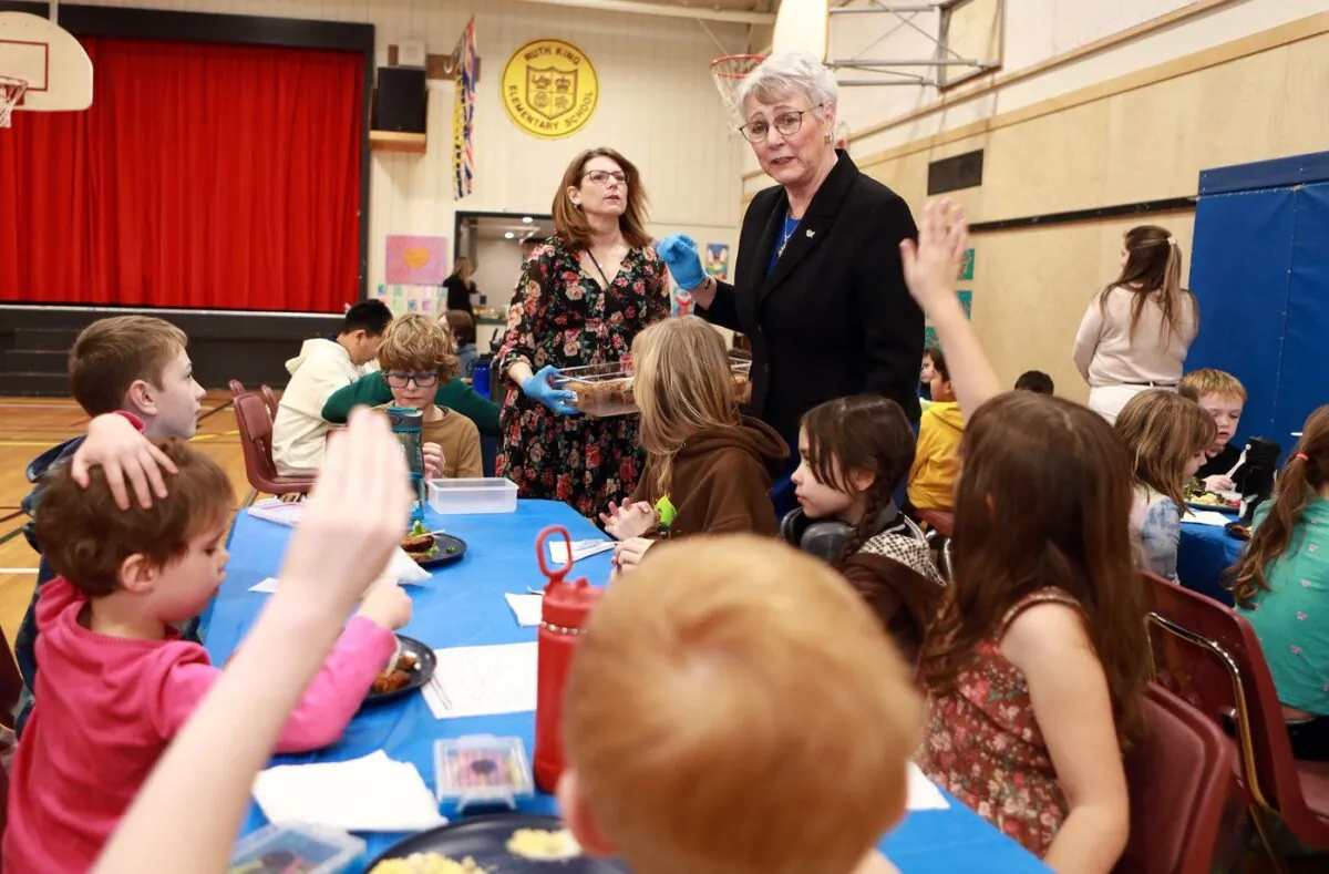 British Columbia Finance Minister Katrine Conroy and school principal Vicki Ives serve up a hot lunch for students at Ruth King Elementary during a photo-op ahead of the budget while in Langford, B.C., Feb. 27, 2023. (The Canadian Press/Chad Hipolito)