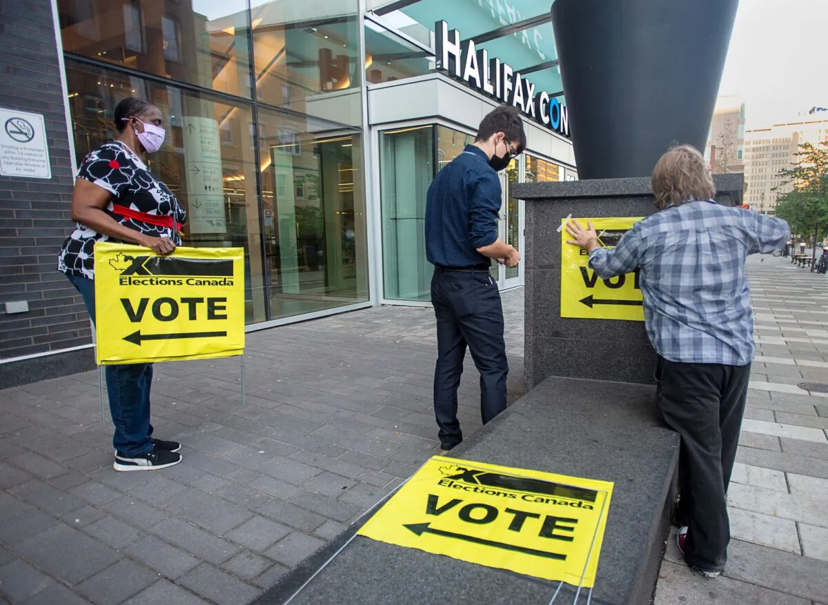 Elections Canada workers place signage at the Halifax Convention Centre in Halifax as they prepare for the polls to open in the federal election on Sept. 20, 2021. (Andrew Vaughan/The Canadian Press)