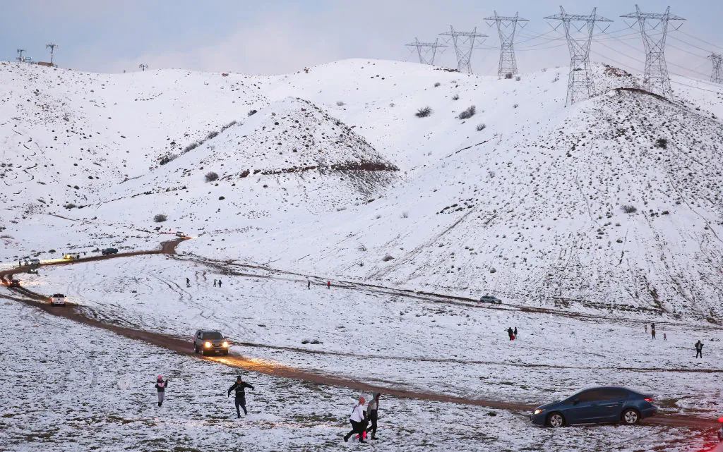 People gather and play on a snow-covered hillside near Palmdale, Calif., on Feb. 26, 2023. (Mario Tama/Getty Images)