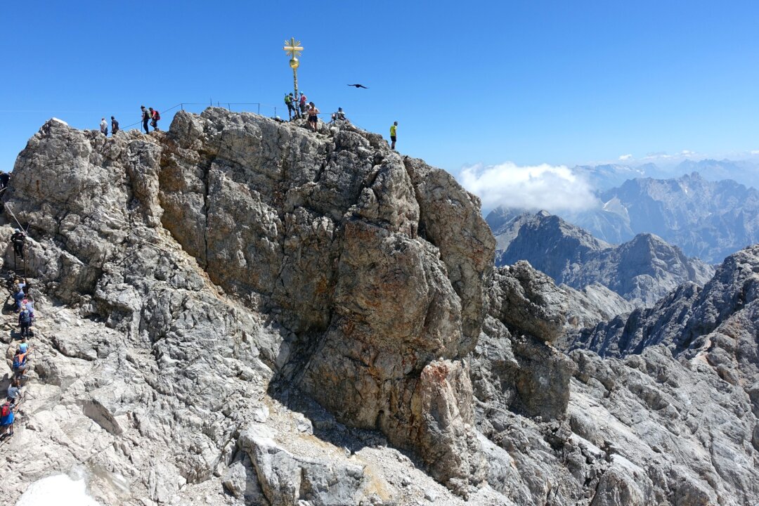 A golden cross marks the top of the 9,700-foot Zugspitze â€“ the highest point in Germany. The mountain straddles the border between Germany and Austria, and lifts from both countries whisk visitors to the top. (Rick Steves)