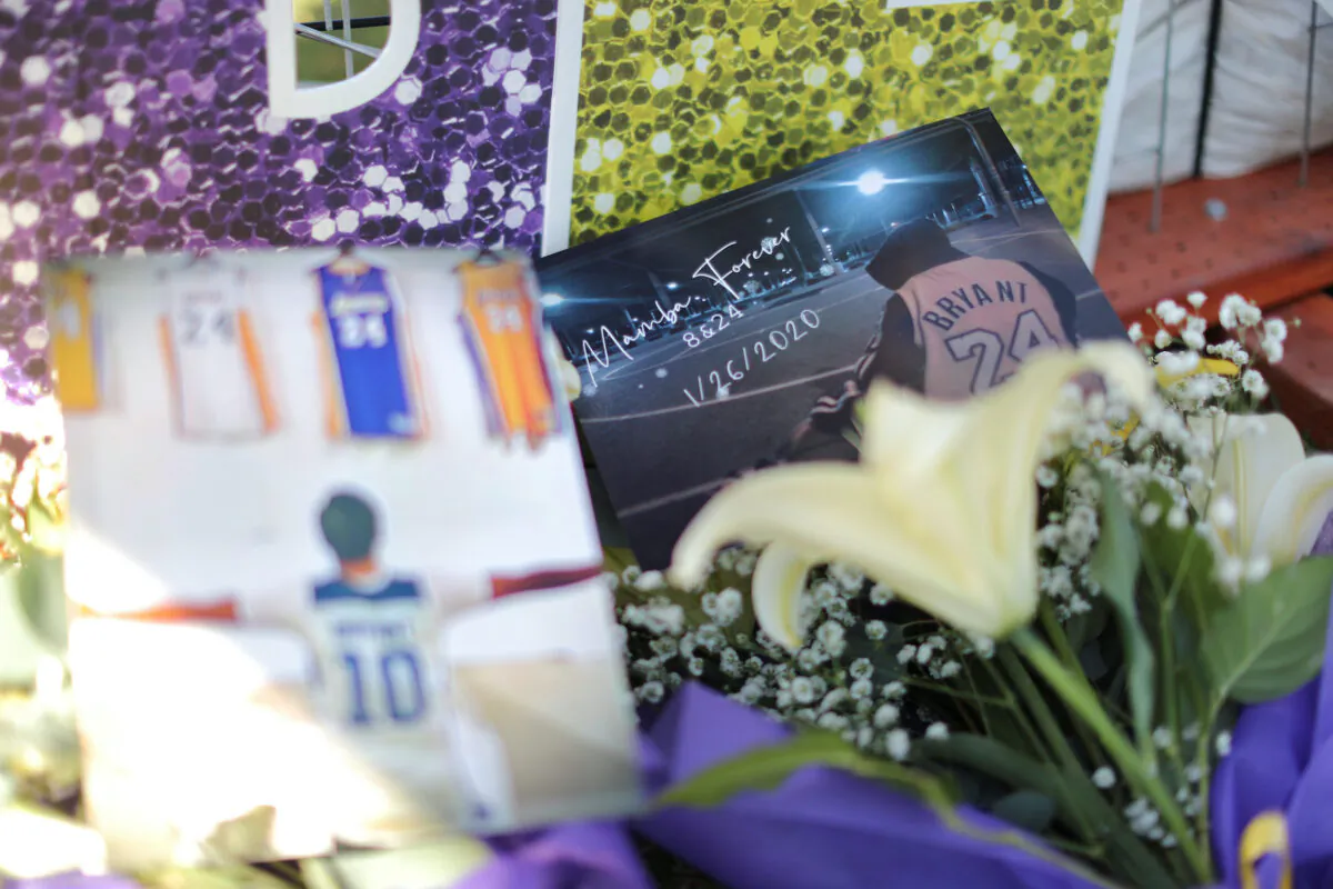 Flowers and pictures are seen as fans gather for a memorial to late Kobe Bryant, who perished alongside his daughter and seven others when their helicopter crashed into a hillside near Los Angeles, outside the Staples Center in Los Angeles, Calif., on Jan. 26, 2021. (Lucy Nicholson/Reuters)