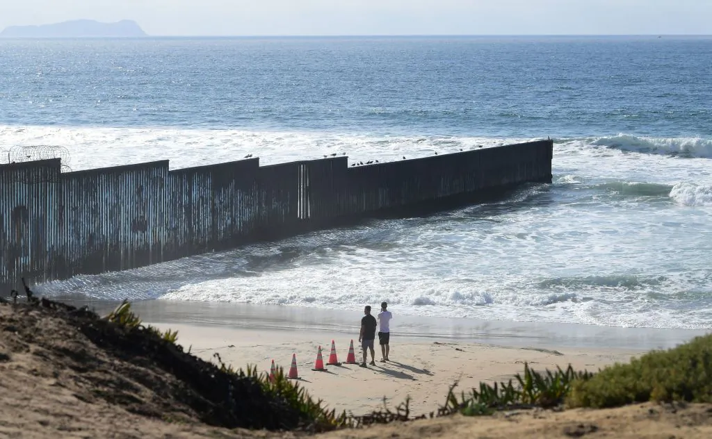 People look towards the US-Mexico border fence that runs into the Pacific Ocean, seen from Imperial Beach outside San Diego in the far southwestern corner of the country on Nov. 7, 2021. (Frederic Brown/AFP via Getty Images)