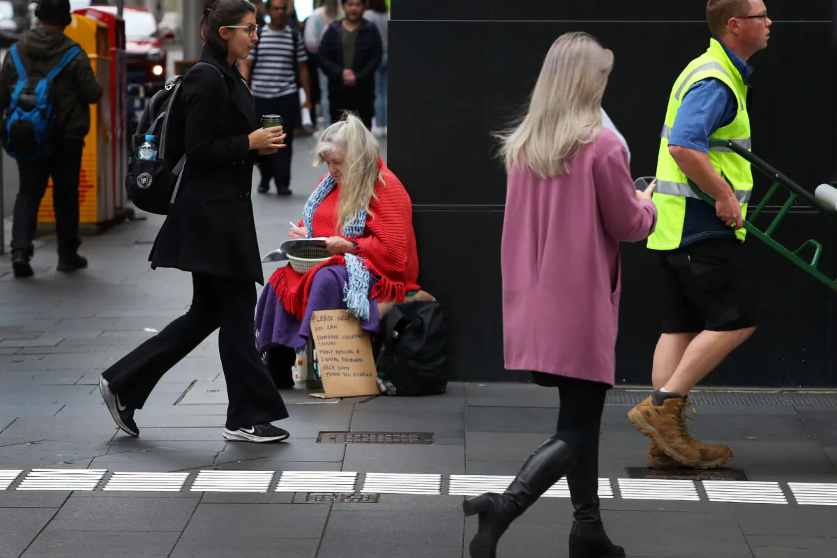 Pedestrians move past a woman sitting on the George Street sidewalk in Sydney, Australia, on Oct. 18, 2022. (Lisa Maree Williams/Getty Images)