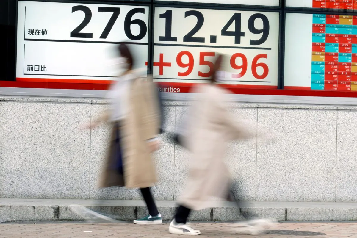 People walk in front of an electronic stock board showing Japan's Nikkei 225 index at a securities firm in Tokyo on March 2, 2023. (Eugene Hoshiko/AP Photo)