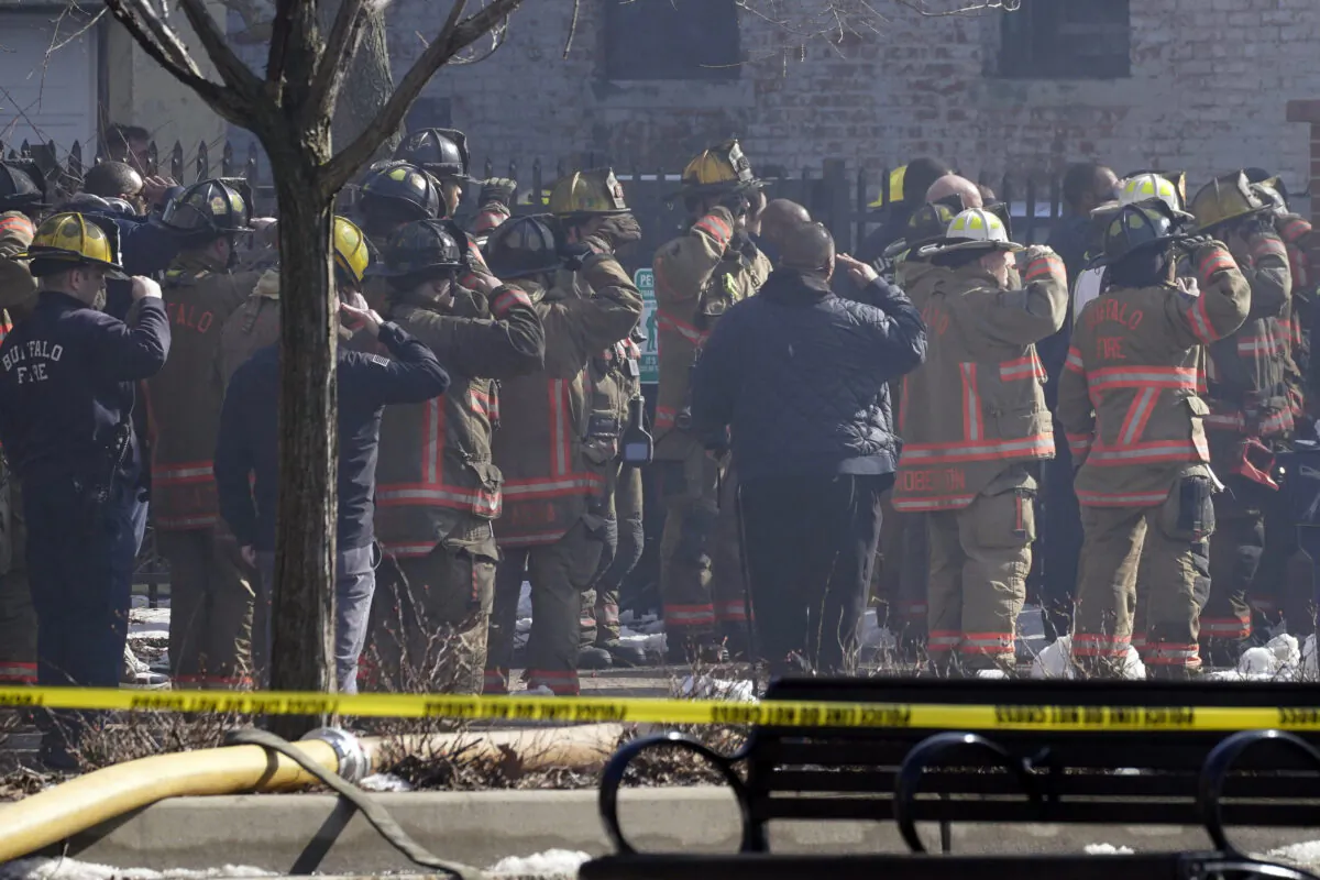 Buffalo firefighters battling a massive, 4-alarm blaze at 745 Main Street line up and salute their fallen colleague as his body is recovered, in Buffalo, N.Y., on  March 1, 2023. (Derek Gee/The Buffalo News via AP)