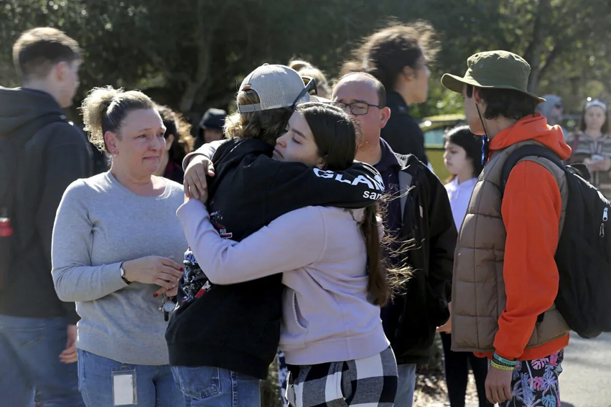 Cameron Gonzalez, 15, hugs fellow student Izzy Sullivan 18, while Cameron's mom, Amy Gonzalez, stands nearby after students were released from the football field following a fatal stabbing at Montgomery High School in Santa Rosa, Calif., on March 1, 2023. (Beth Schlanker/The Press Democrat via AP)