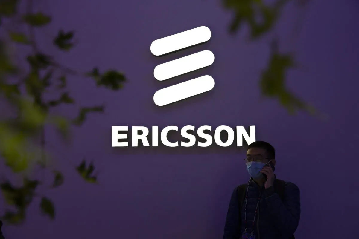 A man wearing a face mask talks on his smartphone near a booth from Swedish technology firm Ericsson at the PT Expo in Beijing on Oct. 14, 2020. (Mark Schiefelbein/AP Photo)