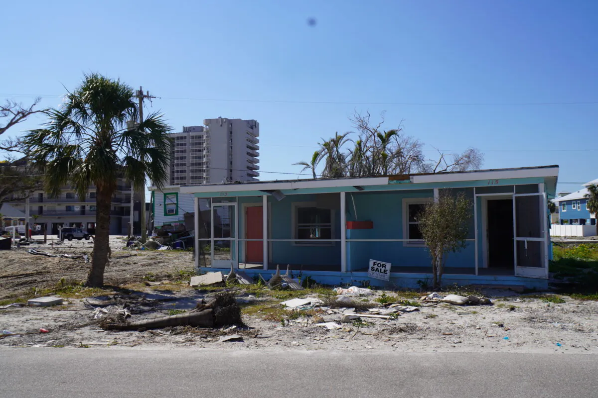 A smashed vacation-rental duplex with a marooned house behind it idles on a side street off Estero Boulevard in Ft. Myers Beach, Fla., in late February, five months after Category 4 Hurricane Ian made landfall nearby. (John Haughey/The Epoch Times)