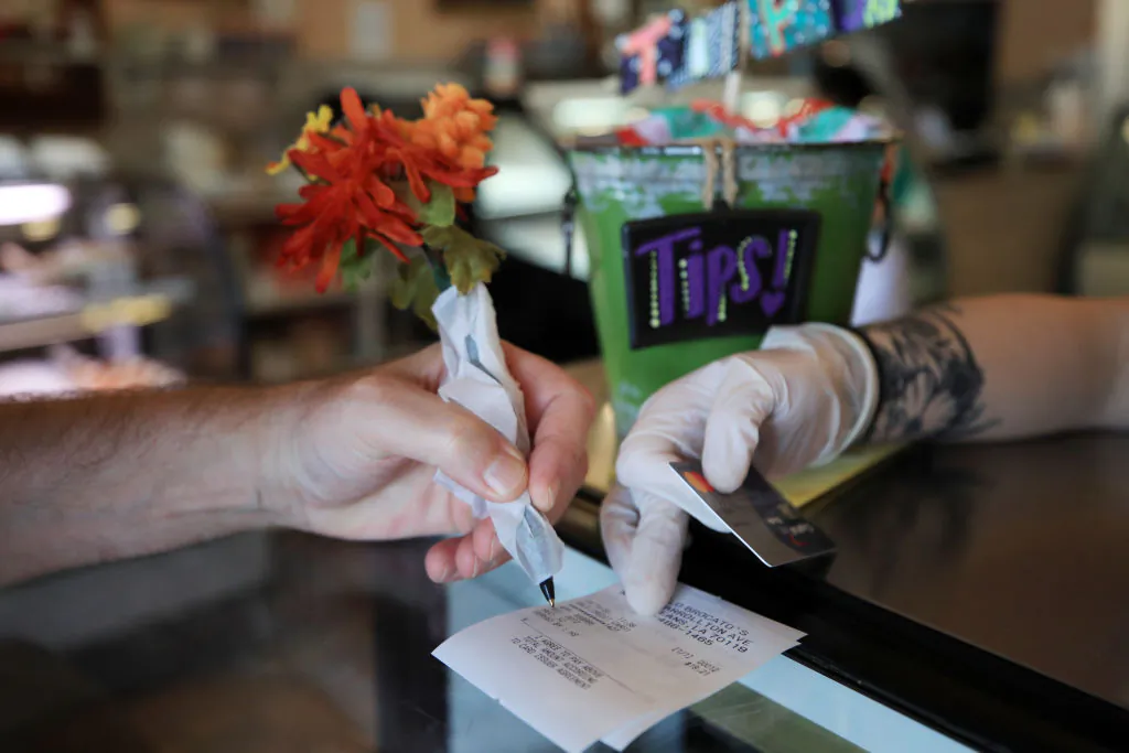 A patron uses a pen wrapped in paper to sign a credit card receipt at Angelo Brocato's Italian Ice Cream Parlor due to COVID-19, in New Orleans, La., on Mar. 19, 2020. (Photo by Chris Graythen/Getty Images)