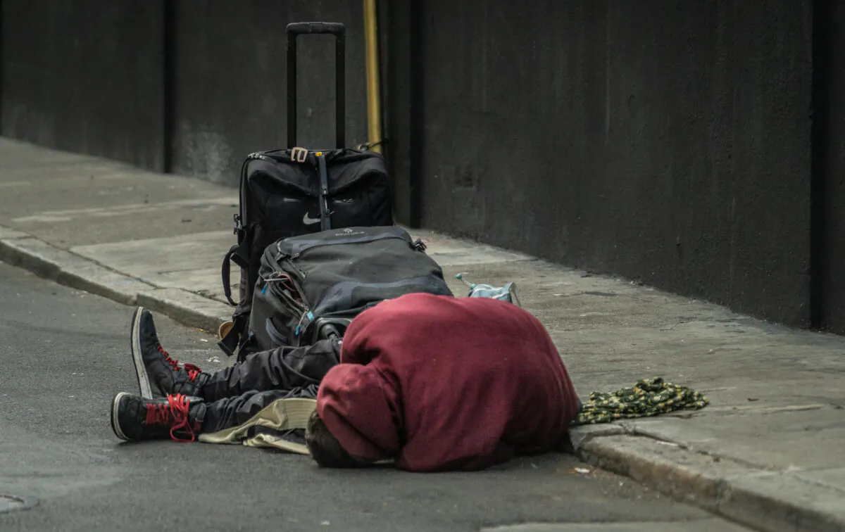 A homeless man lies on a street in the Tenderloin District of San Francisco on Feb. 23, 2023. (John Fredricks/The Epoch Times)