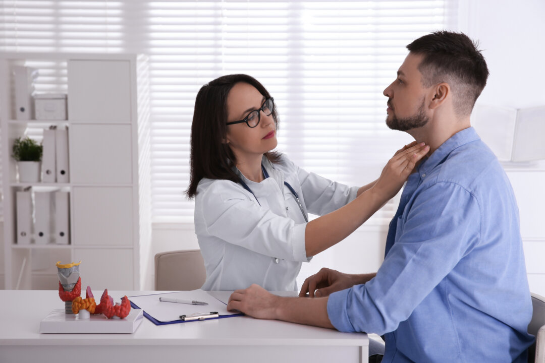 A doctor examines the thyroid gland of a patient in a hospital. (Shutterstock)