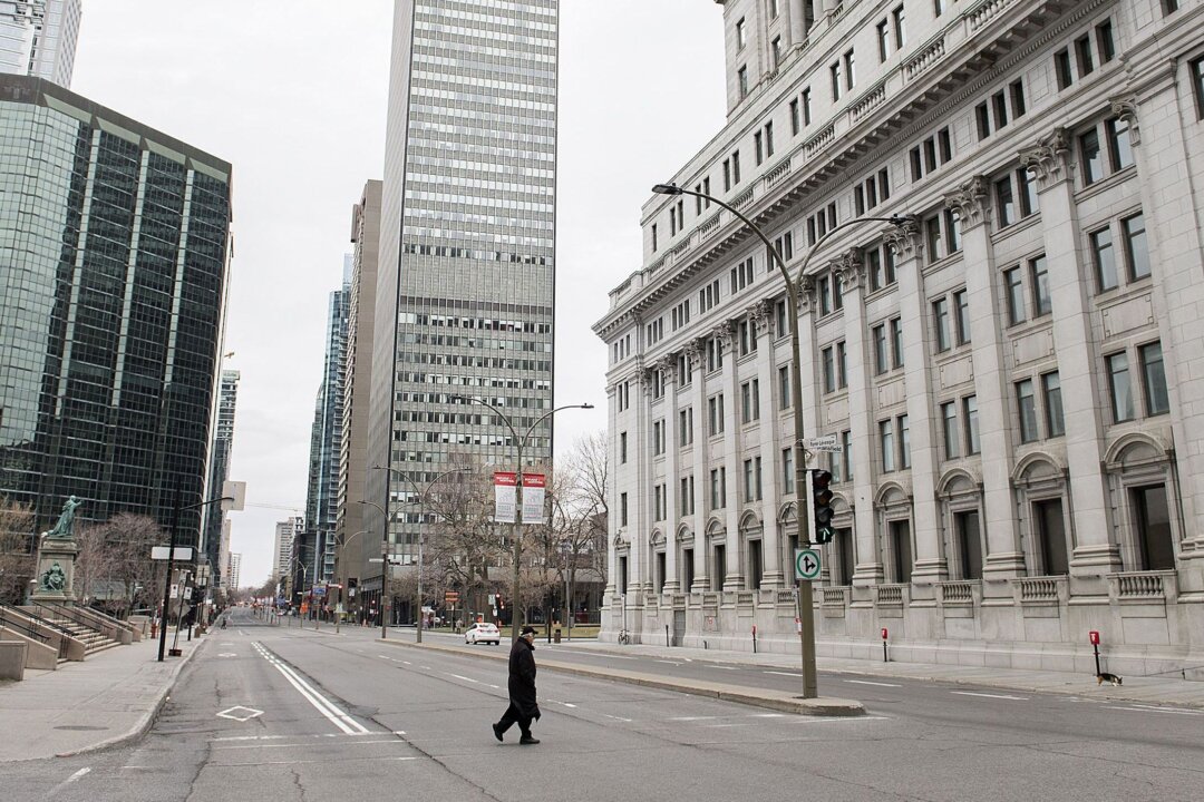 A man crosses an empty street in downtown Montreal during nationwide lockdowns at the beginning of the pandemic, on April 5, 2020. (The Canadian Press/Graham Hughes)