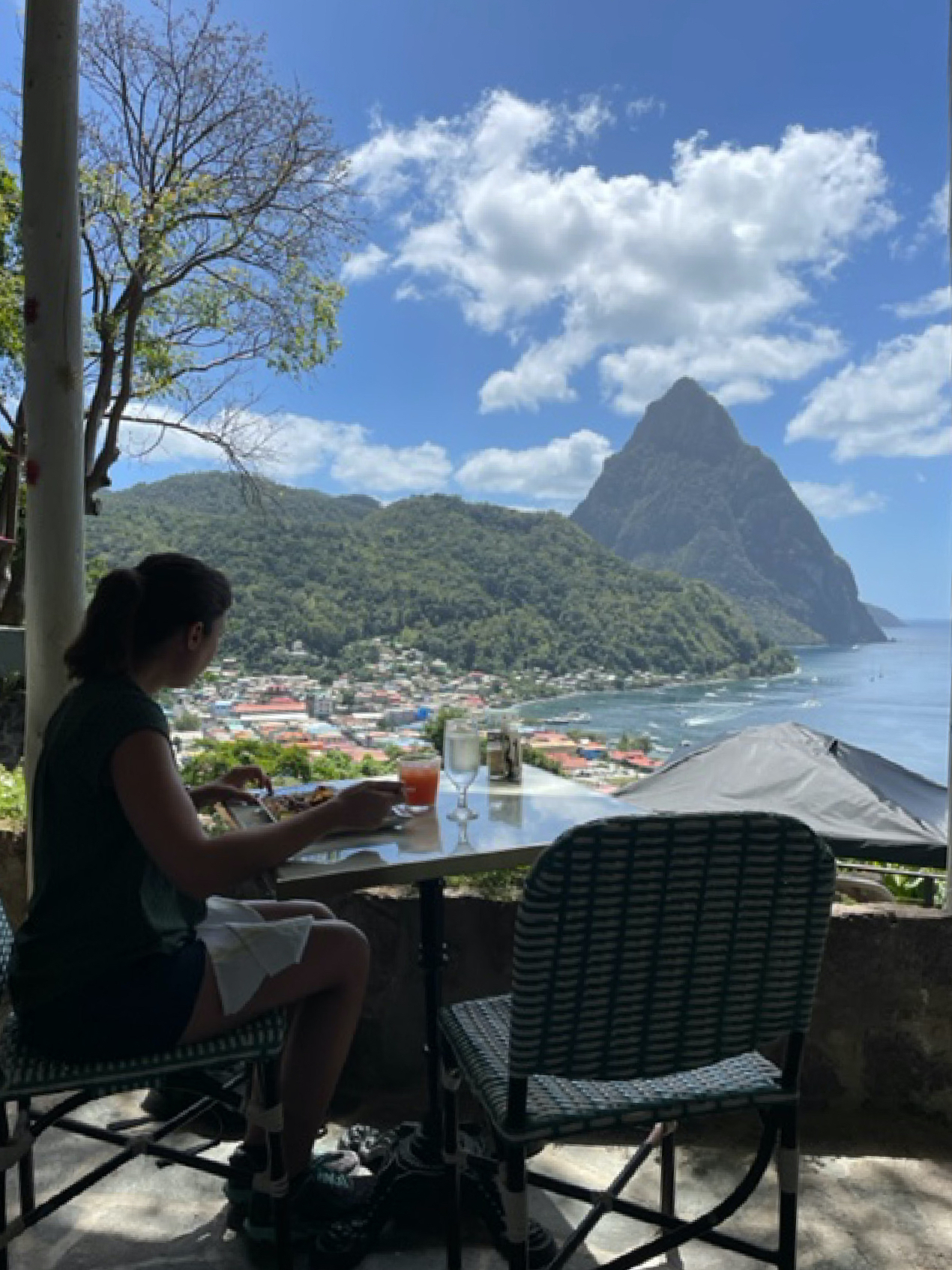 A guest enjoys open-air dining on local Creole cuisine at the Green Fig Resort with Petit Piton in the distance beyond Soufriere, St. Lucia.