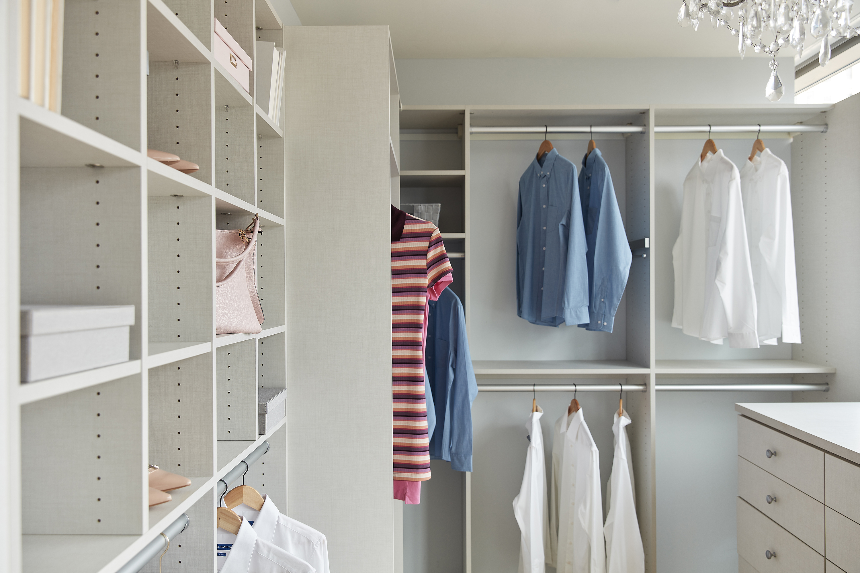 Built-in organization including a built-in dresser helps keep a primary bedroom closet organized.