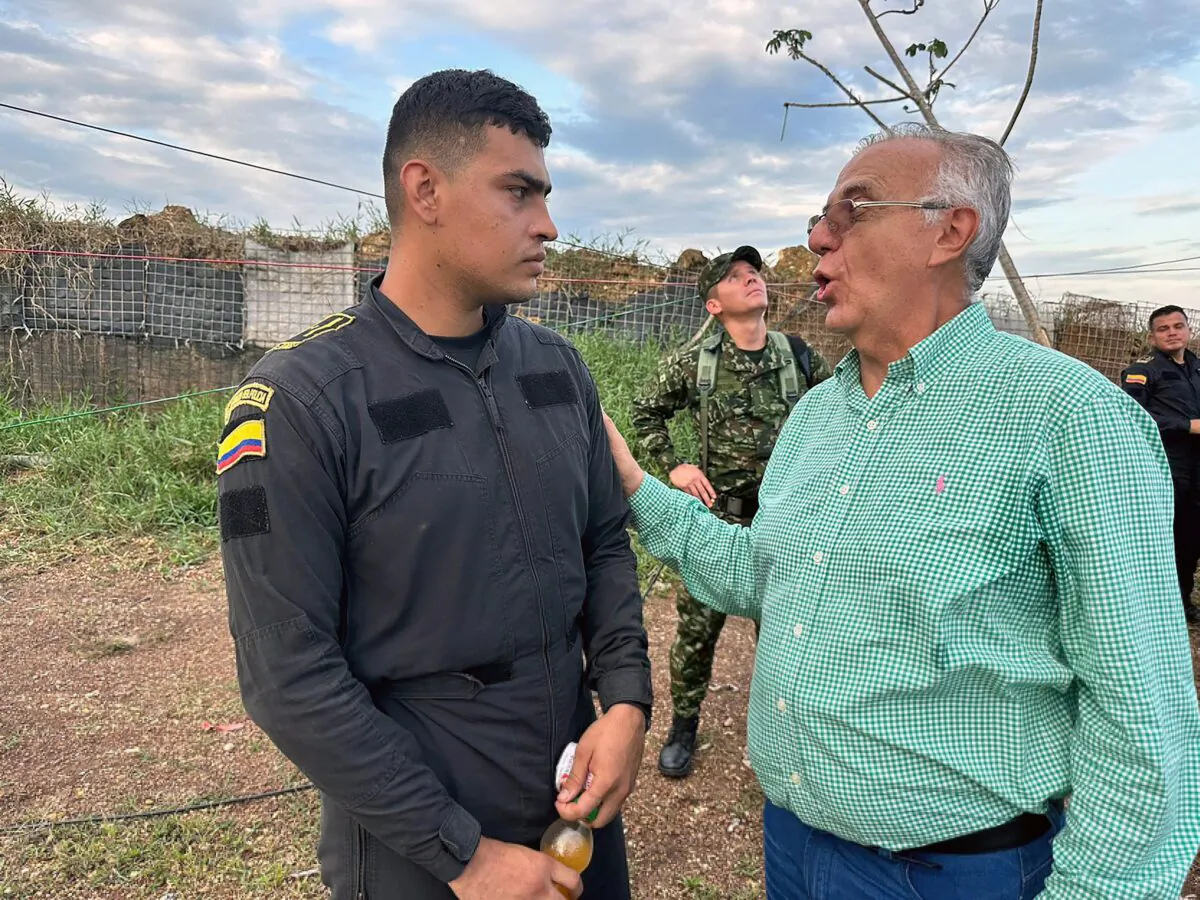 Colombia's Defense Minister Ivan Velasquez speaks with a police officer who, along with other police officers, were detained by rural and indigenous communities, according to authorities, who are demanding that the oil company Emerald Energy build roads in San Vicente del Caguan, Colombia, on March 3, 2023. (Colombian Ministry of Defense/Handout via Reuters)