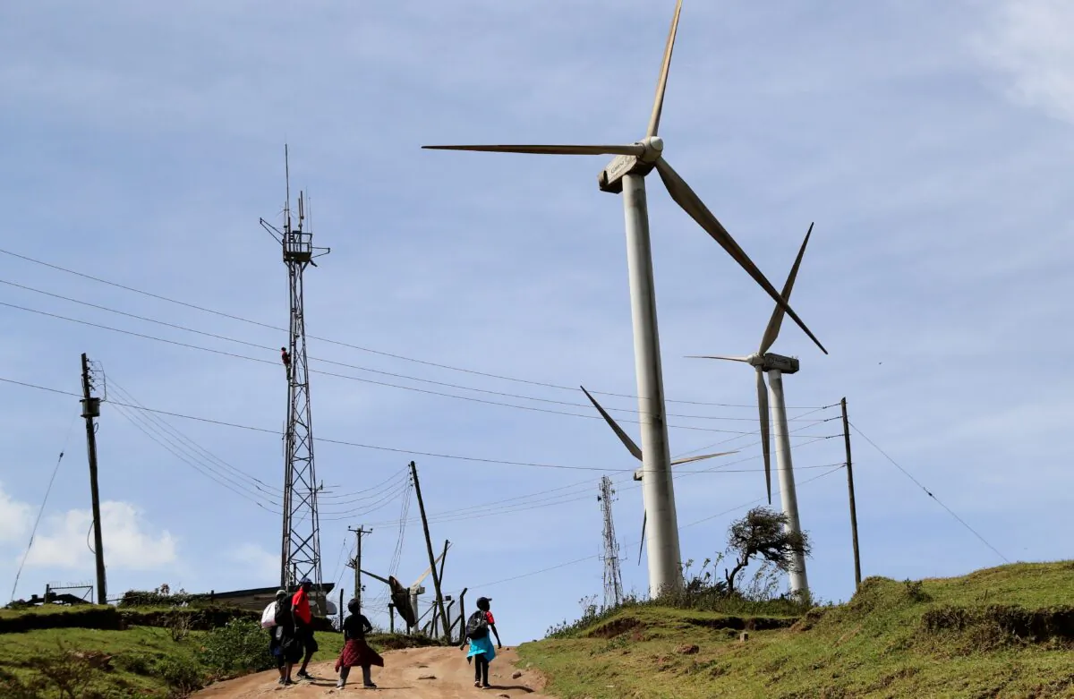 Residents walk past electricity cables near the power-generating wind turbines in Ngong hills, outside Nairobi, Kenya, on Feb. 14, 2022. (Thomas Mukoya/Reuters)