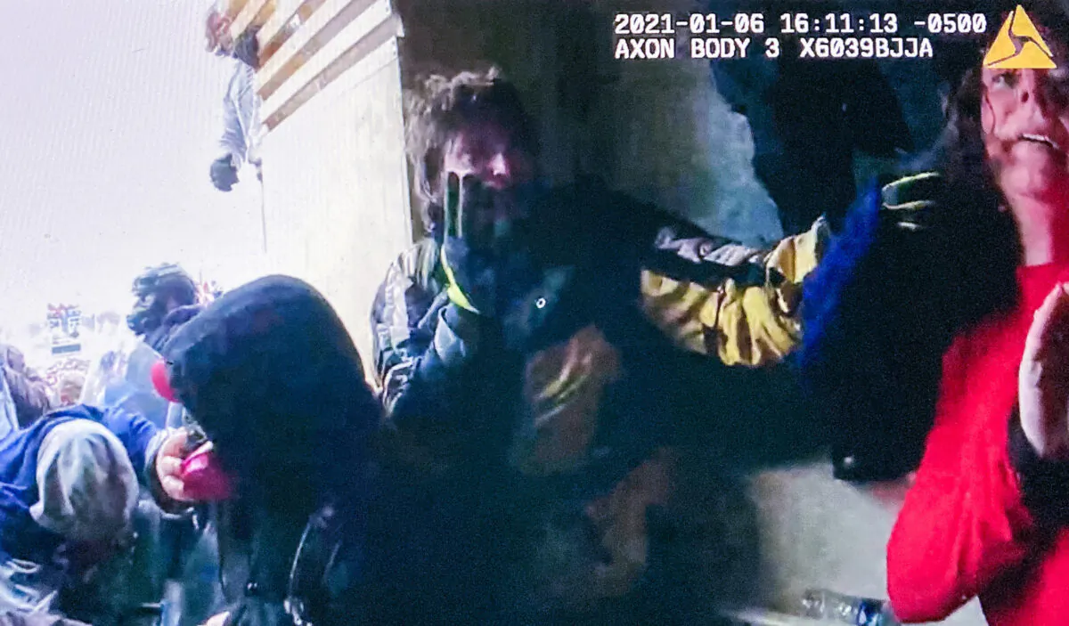 Jan. 6 protester Victoria White (at right) flinches in fear in the Lower West Terrace tunnel at the U.S. Capitol while a bystander yells at police, "No! You're going to kill her!" (Metropolitan Police Department/Screenshot via The Epoch Times)