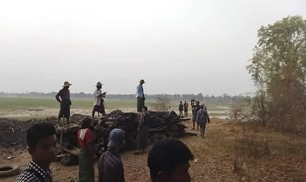 Men stand over a funeral pyre in Tar Taing village, as they prepare to cremate bodies of those found dead in the nearby village of Nyaung Yin, Myinmu township and in Tar Taing village, Sagaing township, central Burma, on March 2, 2023. (UGC via AP)
