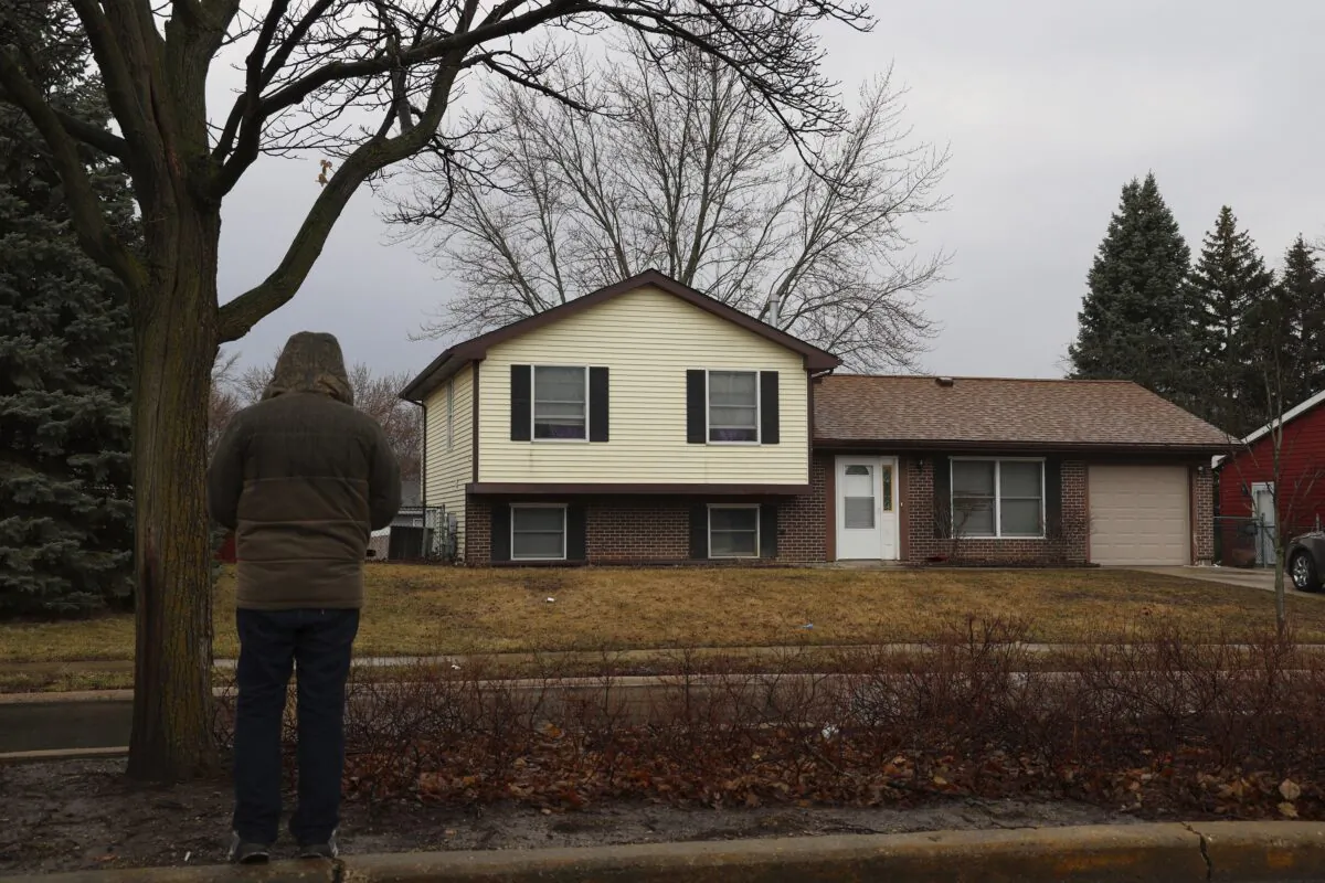 A man stands and looks at the home in Bolingbrook, Ill., on March 6, 2023, where three people were fatally shot, and another person was wounded Sunday night. (Stacey Wescott/Chicago Tribune via AP)