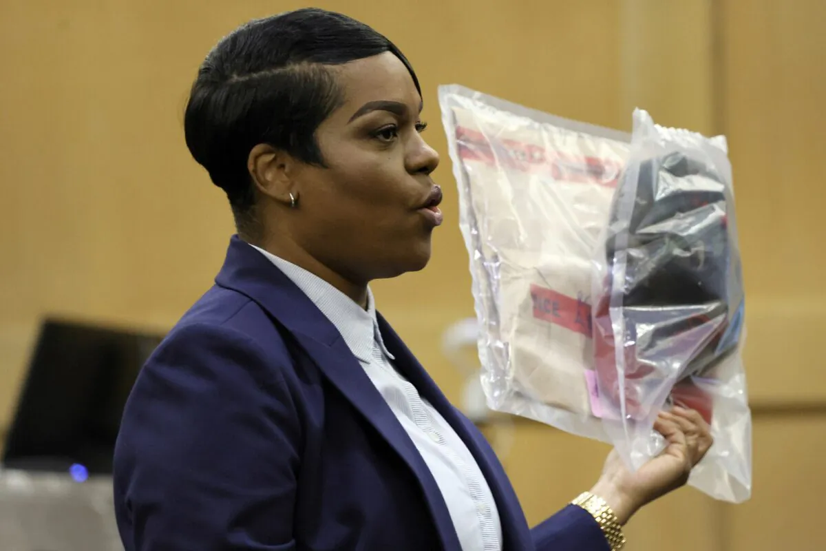 During her closing arguments in the XXXTentacion murder trial, Assistant State Attorney Pascale Achille holds up a camouflage hat with a red brim that was seen worn by shooting suspect Michael Boatwright in multiple surveillance videos included as evidence in the case, at the Broward County Courthouse in Fort Lauderdale, Fla., on March 7, 2023. (Amy Beth Bennett/South Florida Sun-Sentinel via AP, Pool)