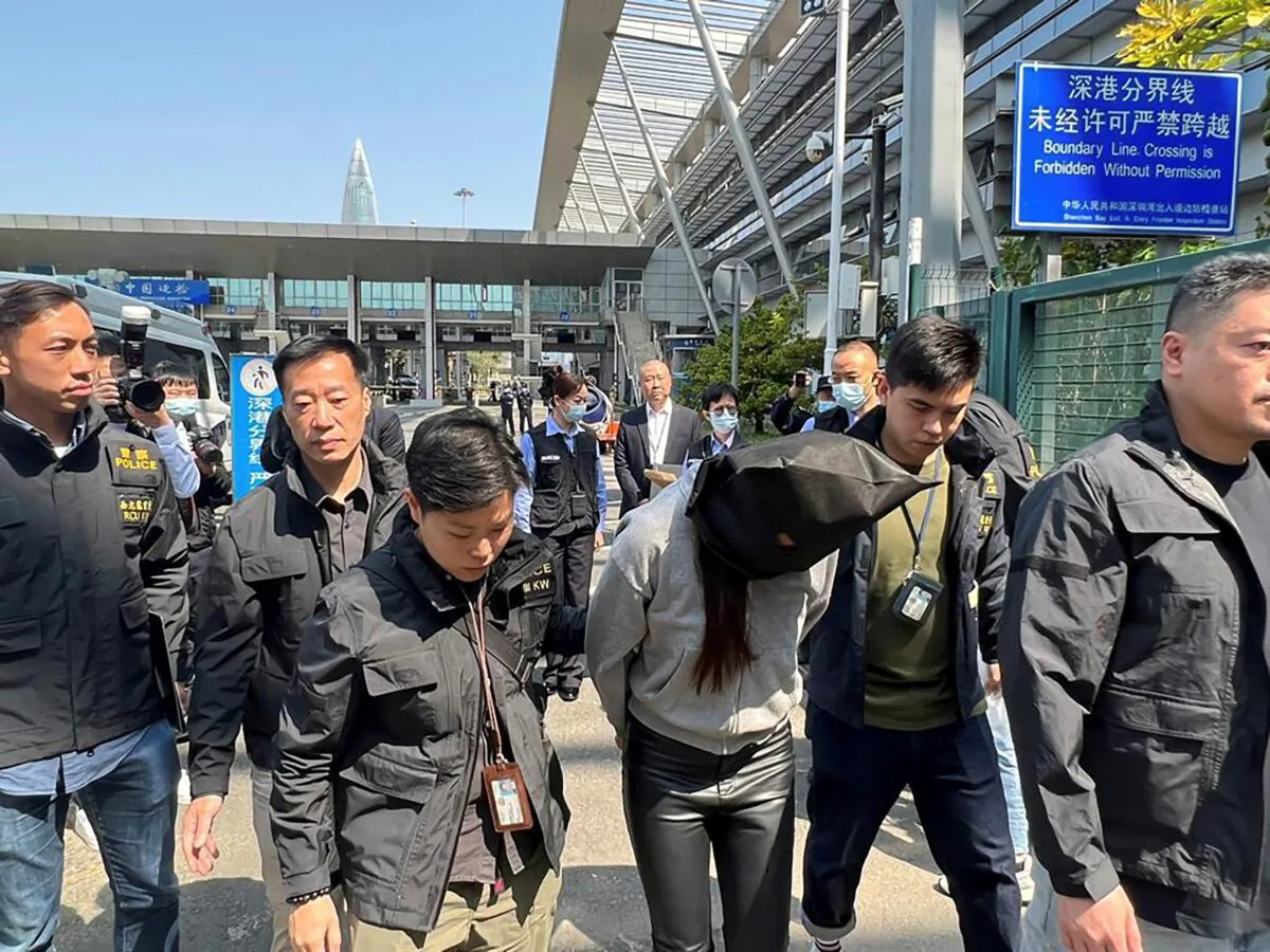 Hong Kong police escort a suspect at the Shenzhen Bay Port border crossing in Hong Kong, on March 7, 2023. (Information Services Department via AP)