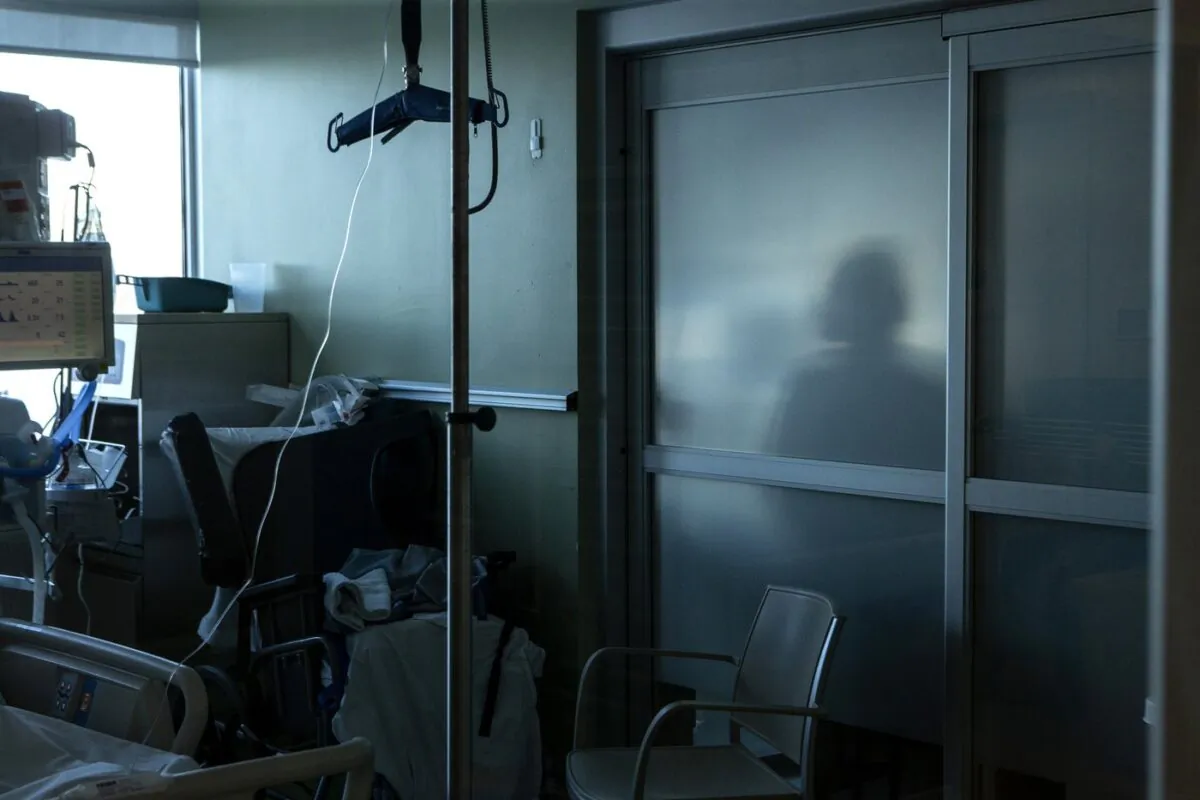A nurse is silhouetted behind a glass panel as she tends to a patient in the Intensive Care Unit at an Ontario hospital, on Jan. 25, 2022. (The Canadian Press/Chris Young)
