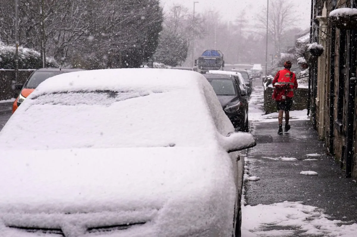 A postal delivery worker wearing shorts in heavy snow fall during his delivery rounds in Oldham, Greater Manchester, on March 9, 2023. (Peter Byrne/PA Media)