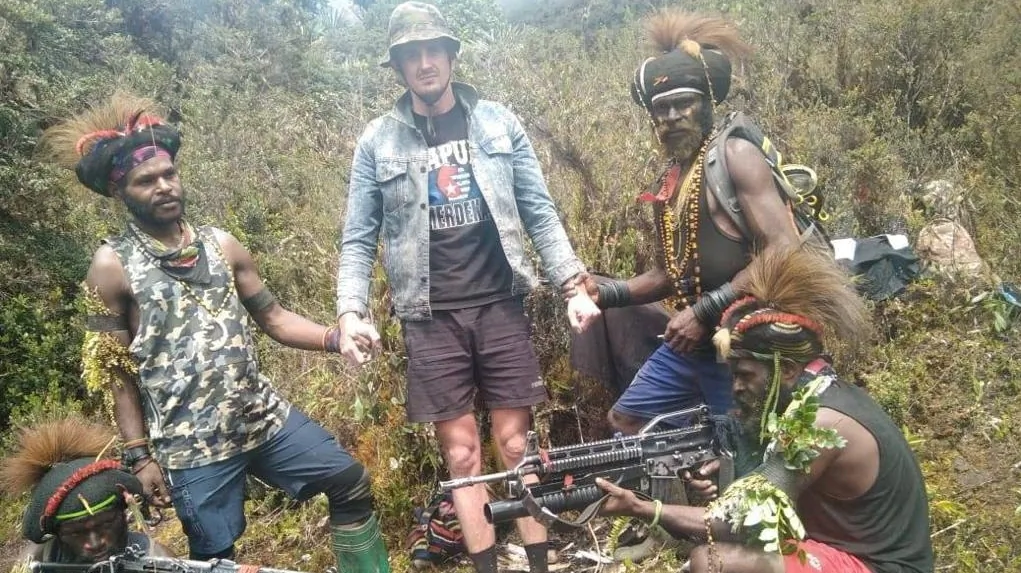 A man, identified as Philip Mehrtens, the New Zealand pilot who is said to be held hostage by a pro-independence group, stands among the separatist fighters in Indonesia's Papua region, in this undated picture released on Feb. 14, 2023. (The West Papua National Liberation Army (TPNPB)/Handout via Reuters)