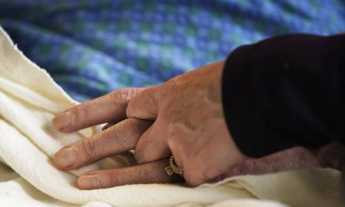 A patient has his hand held at a hospital, in Minneapolis, May 3, 2021. (The Canadian Press/David Joles-Star Tribune via AP)
