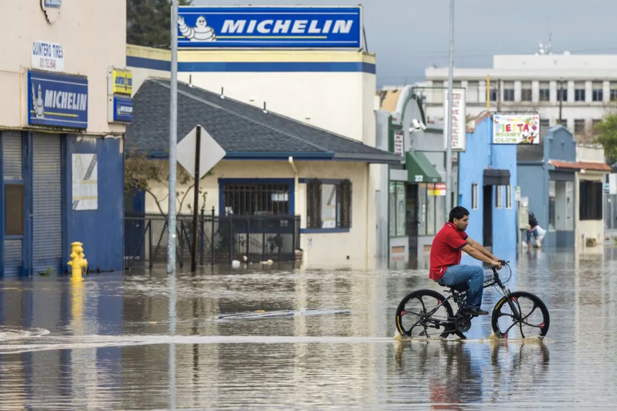 A man rides his bicycle through floodwaters in Watsonville, Calif., on March 11, 2023. (Nic Coury/AP Photo)