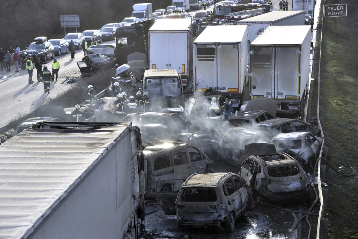 Firefighters work among smoldering cars after several trucks and cars crashed on M1 motorway near Herceghalom, Hungary, on March 11, 2023. (Peter Lakatos/MTI via AP)