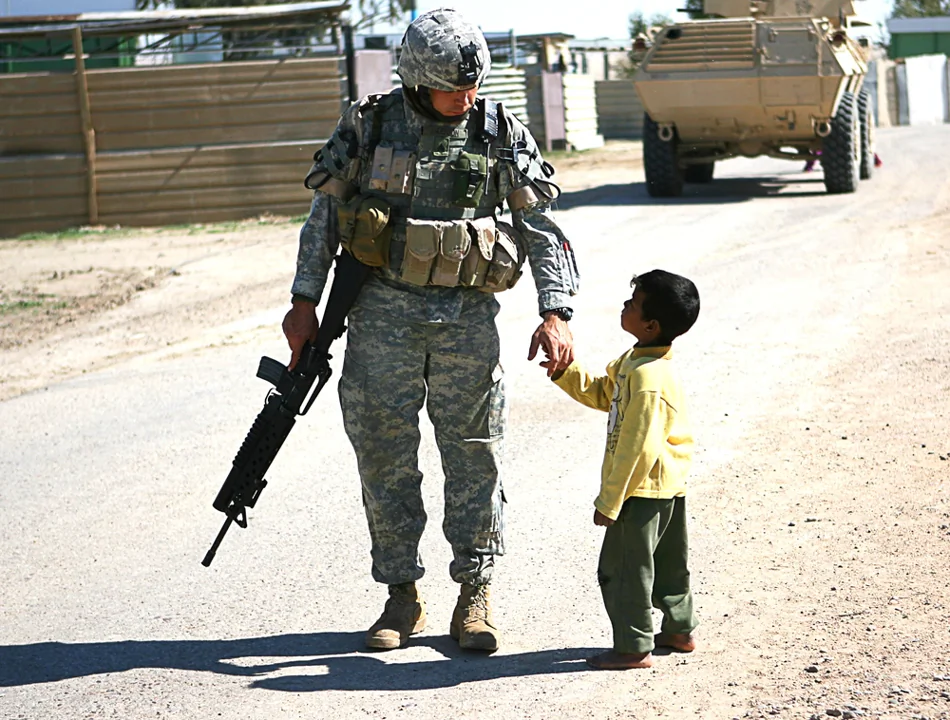 Sgt. Robert R. Anderson, infantryman, interacts with a local Iraqi child in a village outside of Camp Taqaddum, Iraq, on Mar. 12th, 2006. (Photo by Cpl. Daniel Redding, 1st Marine Logistics Group)
