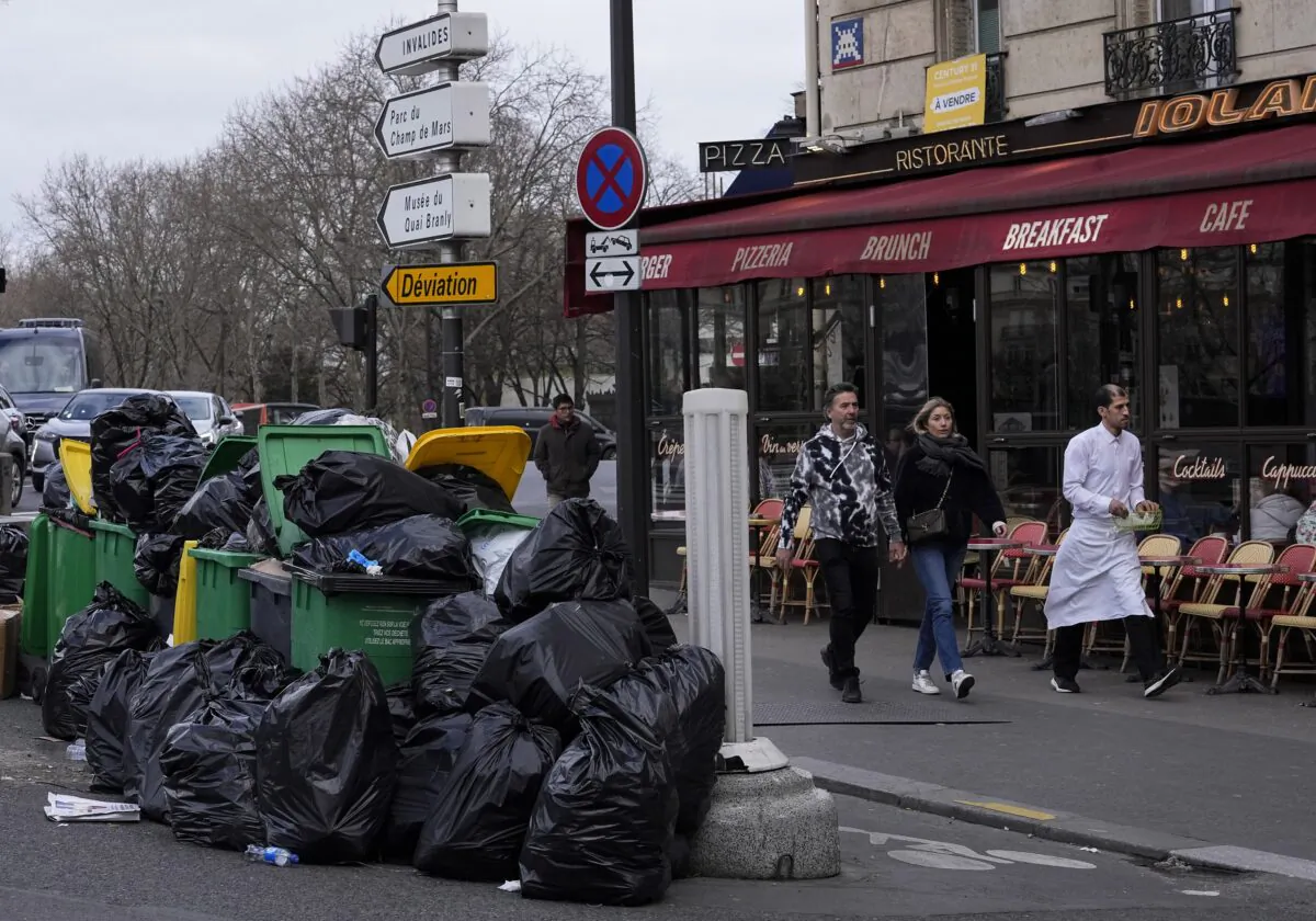 People walk past not collected garbage cans next to the Senate in Paris on March 12, 2023. (Michel Euler/AP Photo)