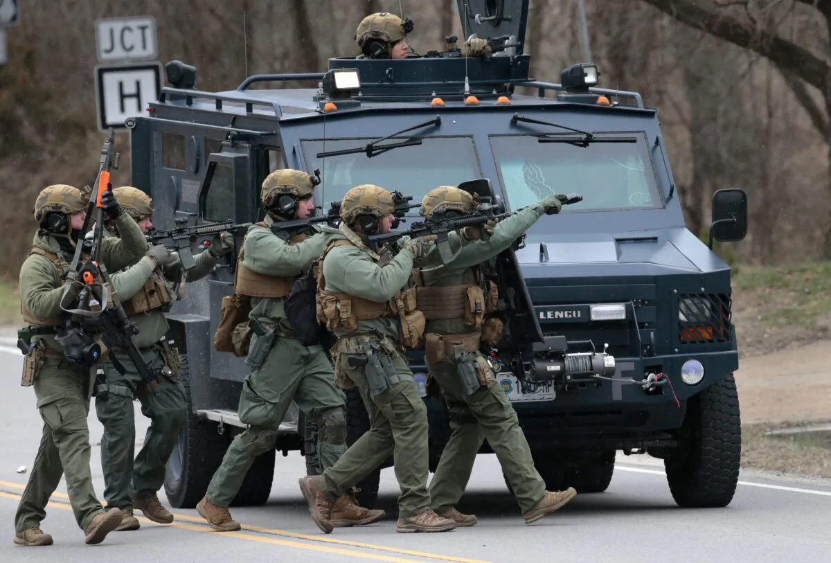 A tactical unit from the Missouri Highway Patrol moves to enter a home where a man was believed to be hiding after being accused of shooting two Hermann police officers Sunday night, on March 13, 2023. (Robert Cohen/St. Louis Post-Dispatch via AP)