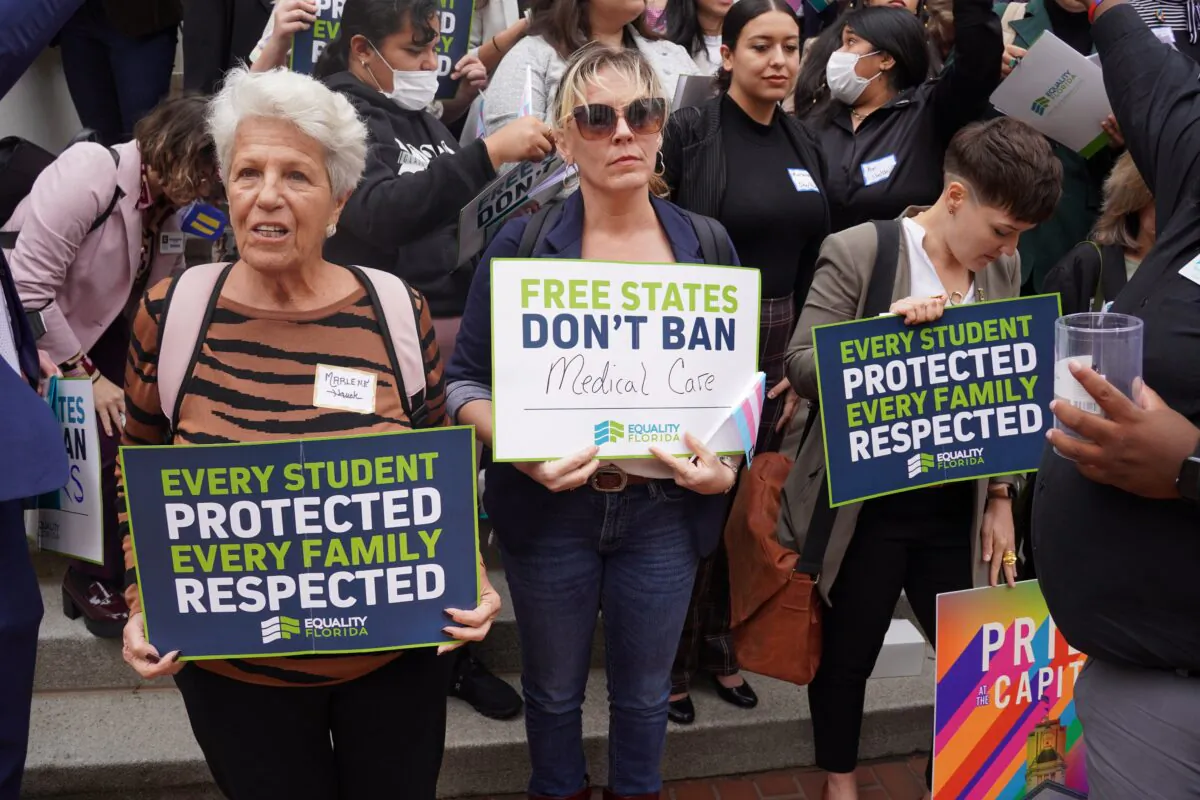 Protestors at an LGBT rally at the Florida Capitol in Tallahassee on March 13, 2023 hold signs that read "Every Student Protected, Every Family Respected" and "Free States Don't Ban Medical Care." (Dan M. Berger/The Epoch Times)