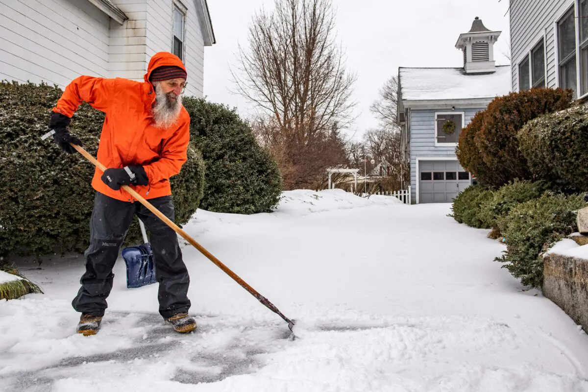 A man breaks up ice and sleet on his driveway during a winter storm in Concord, N.H., on Feb. 4, 2022. (Joseph Prezioso/AFP via Getty Images)