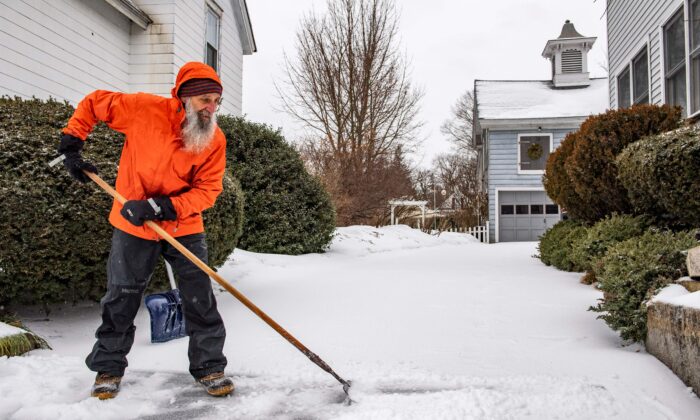 A man breaks up ice and sleet on his driveway during a winter storm in Concord, N.H., on Feb. 4, 2022. (Joseph Prezioso/AFP via Getty Images)