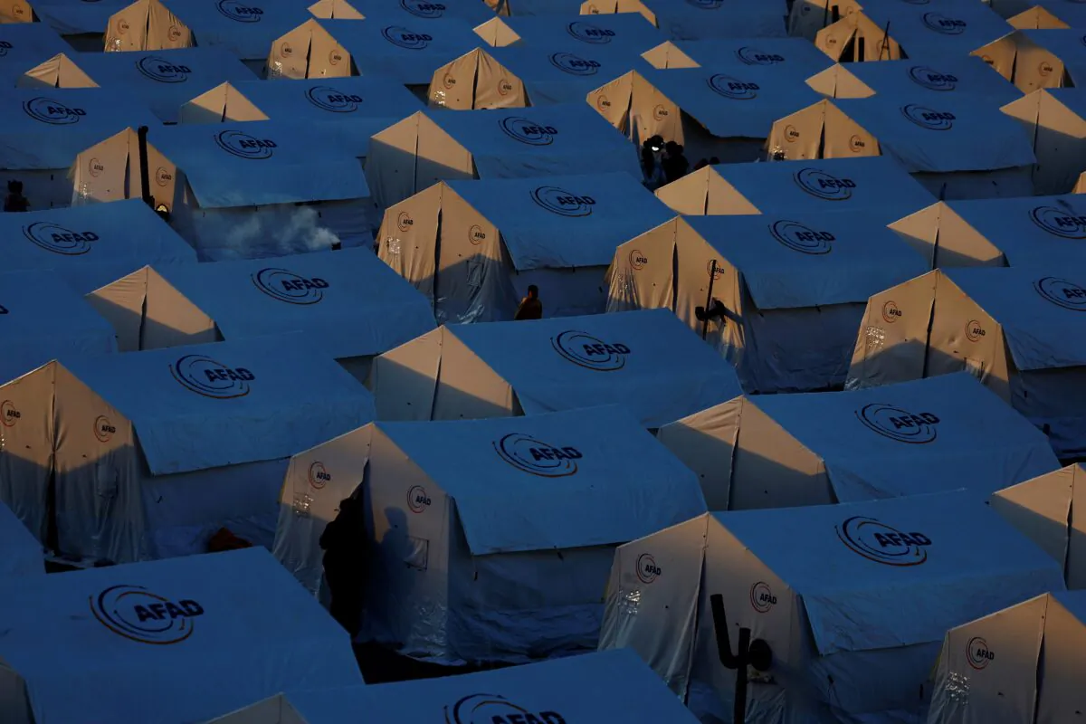 Displaced people walk outside tents at a camp for earthquake survivors at KSU Avsar university campus in the aftermath of a deadly earthquake in Kahramanmaras, Turkey, on March 9, 2023. (Susana Vera/Reuters)