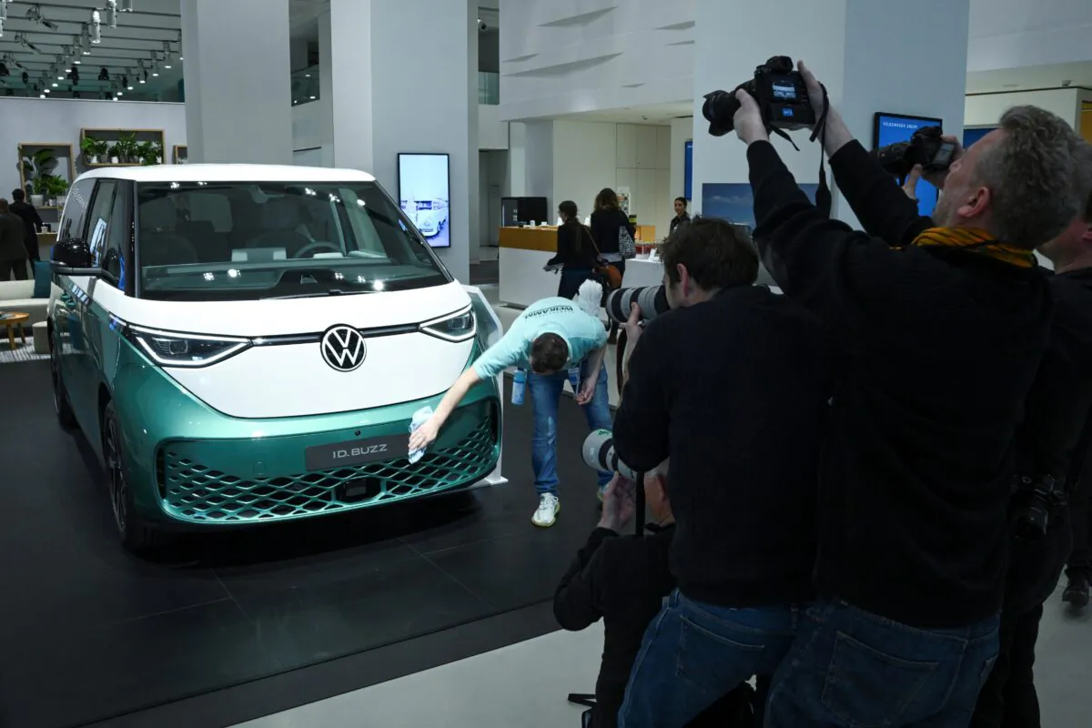 Photographers take pictures as a worker cleans a Volkswagen ID. Buzz EV car, on the day of the annual news conference of the Volkswagen Group at DRIVE.Volkswagen Group Forum, in Berlin, on March 14, 2023. (Annegret Hilse/Reuters)