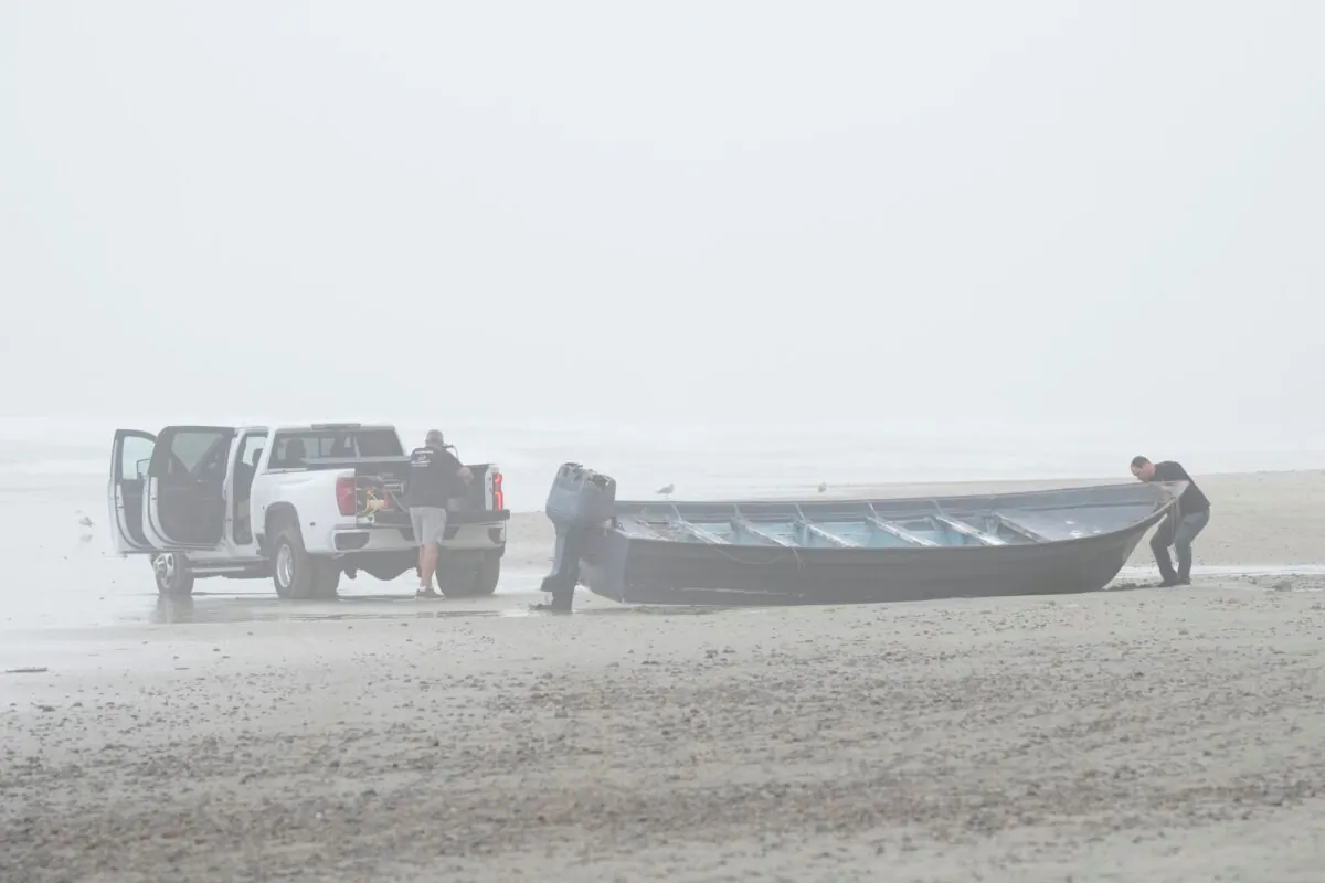 Boat salvager Robert Butler, (L). and KC Ivers, (R), prepare to move one of two boats on Blacks Beach, in San Diego, Calif., on March 12, 2023. (Gregory Bull/AP Photo)