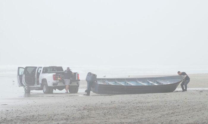 Boat salvager Robert Butler, (L). and KC Ivers, (R), prepare to move one of two boats on Blacks Beach, in San Diego, Calif., on March 12, 2023. (Gregory Bull/AP Photo)