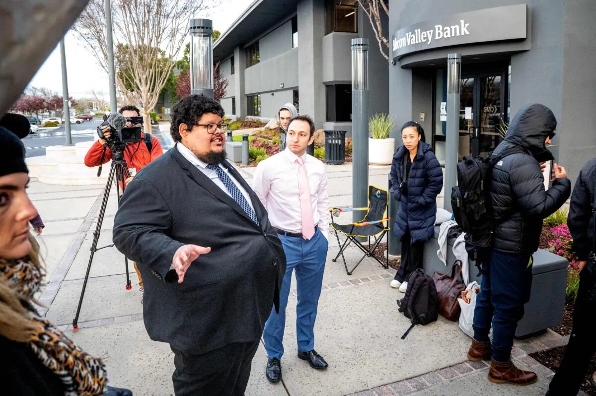 FDIC representatives Luis Mayorga (L) and Igor Fayermark assure Silicon Valley Bank customers that their money is available before the opening of a branch at SVBs headquarters in Santa Clara, Calif., on March 13, 2023. (Noah Berger/AFP via Getty Images)