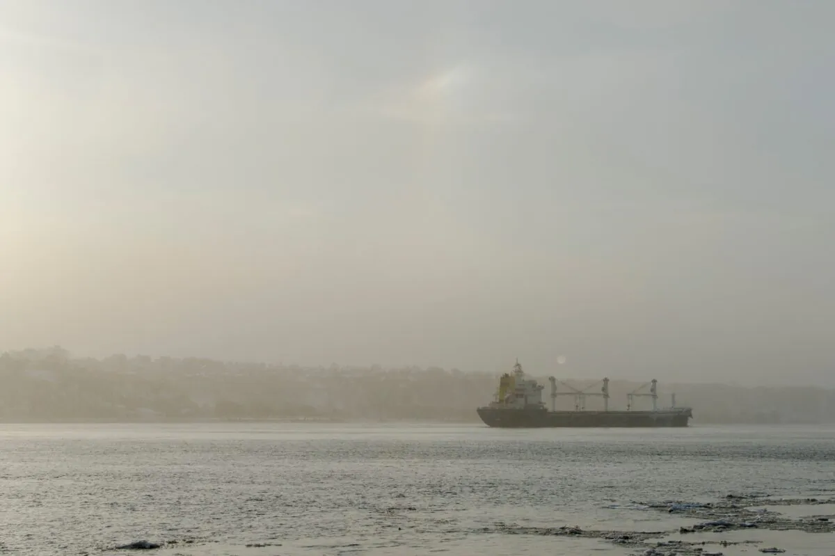 A barge floats down the Saint Lawrence River near the Quai Chouinard as the sun rises over Quebec City and Levis, Quebec, on Dec. 9, 2021. (Andrej Ivanov/AFP via Getty Images)