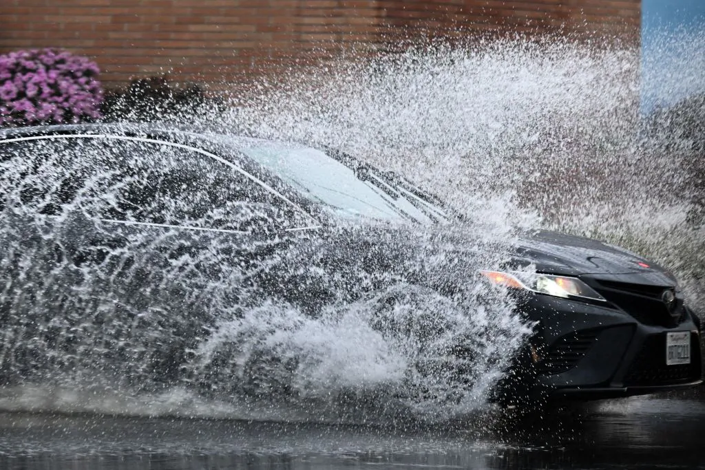 A car drives in the rain through storm water during a winter storm Los Angeles, on March 14, 2023. (Patrick T. Fallon/AFP via Getty Images)